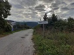 A sign with Cyrillic writing on it sticking out of the ground next to a road