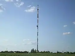 Tall communications tower on flat ground, with guy wires