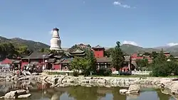Temple buildings with red-painted walls near a body of water
