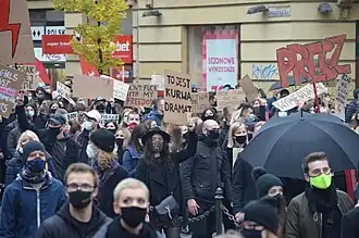 A large crowd of protesters holding signs promoting women's rights in Polish