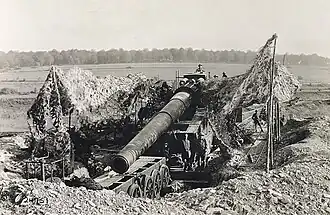 A gun assigned to the US Army in a revetment. It has been jacked up and the bogies are being removed.