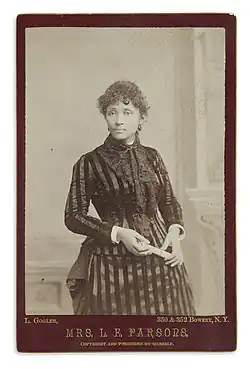 Three quarter length photograph of standing woman in striped dress