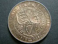 A silver coin, with three shields on it