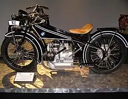 A shiny black Art Deco motorcycle of 1923 with a BMW logo on the gas tank and a boxer twin engine.