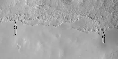 Close view of mantle, as seen by HiRISE under HiWish program Arrows show craters along edge which highlight the thickness of mantle. Location is Ismenius Lacus quadrangle.