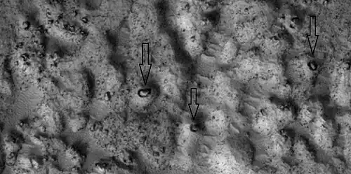 Close view of ejecta, as seen by HiRISE under HiWish program. Note: Arrows show examples of boulders sitting in pits.