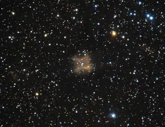fuzzy orange shape in the center of a field of point-like star glows against a black background