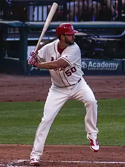 A man, wearing the Cardinals' grey road uniform and dark blue cap with the interlocking "STL" logo, prepares to deliver a pitch with the baseball in his right hand.
