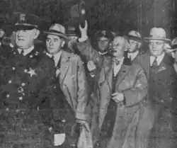 Photograph of Al Smith being escorted by police officers