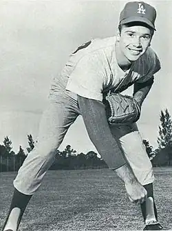 A man in a light baseball uniform and dark cap