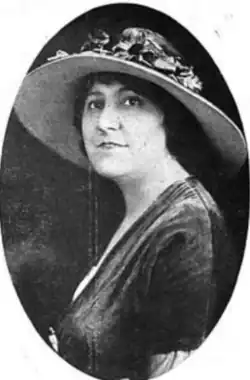 A white woman with dark hair, wearing a brimmed hat, in an oval fame