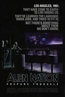A black poster. Above in bold letters are the lines: "Los Angeles, 1991." "They have come to earth to live among us." "They've learned the language." "Taken jobs." "And tried to fit in." "But there's something about them we don't know." Below, in large typeface is the line: "Alien Nation" and in smaller typeface, the line: "Prepare Yourself," with the film credits underneath. In the background are three extraterrestrials standing on a street corner. One of the figures is a female standing next to a waste basket and three newspaper stands, holding a jacket over her shoulders. Behind her is a bar that features alien typography on its walls. Two extraterrestrials who are hanging out inside the bar, can be seen through its glass window.