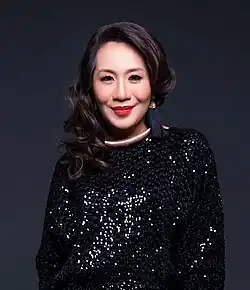 close-up photo of Amelina wearing a black sparkling top, smiling directly at camera