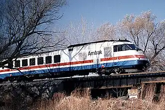 A white passenger trainset with red, white, and blue stripes of equal width on the side under the windows