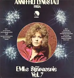 A curly-haired woman in a red suit and dress reclining on a chaise and facing forward. The text reads "ANNI-FRID LYNGSTAD, FRIDA, EMI:s Stjärnserie Vol. 7".