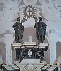 Saints Faustino and Giovita and two angels with the palms of martyrdom and the Holy Cross, bronze sculptures at the top of the tomb