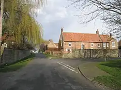 A rural village road with high walls and stone built houses