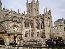 Yellow stone building with large arched windows and a tower.