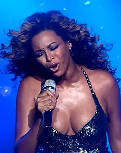 The upper body of Beyoncé is shown as she sings into a microphone