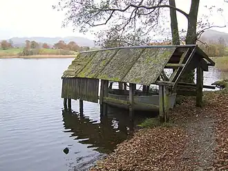 A derelict boathouse extending out onto a lake