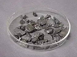 Small chips of lustrous gray metal in a glass dish