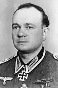A man wearing a military uniform with an Iron Cross displayed at the front of his uniform collar.
