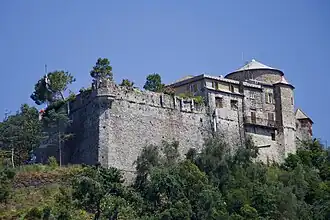 Stone castle overlooking the sea, surrounded by greenery