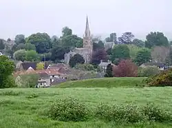 A church with spire surrounded by trees and houses.
