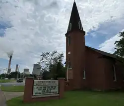 Cheshire Baptist Church, with smoke stacks in the background, in 2025.