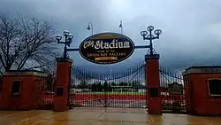 A brick and metal fence and gate with a sign above it that says "City Stadium"