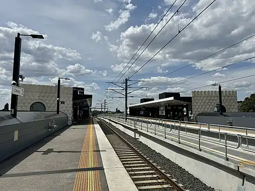 Looking north from Platform 2, showing station building and shelter on each side of the northern end of the station.