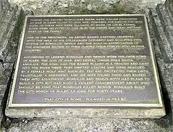 Brass plaque with gold lettering on a painted black background.