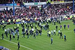 A large number of spectators running onto the field