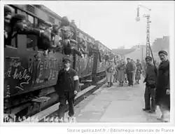 Photograph of several cars filled with conscripts leaving the platform.