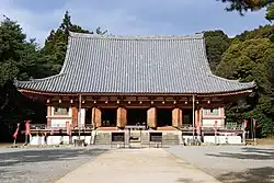 Wooden building with hip-and-gable roof, white walls, vermillionred beams and an open veranda.