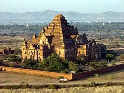Another large temple lit by the sun, with a bus for scale