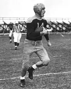 Don Hutson in a Green Bay Packers uniform carrying the ball down a football field.