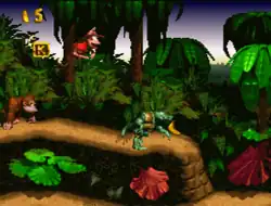 From a side-scrolling perspective, Diddy Kong jumps in the game's first level, Jungle Hijinks. Donkey Kong trails behind him to the left, while a Kremling enemy hobbles away from him on the right.