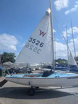 A Mark 1 GRP rigged for heavy weather sailing. Its main sail has two reefs, its jib is furled, and it is equipped with a mast float.