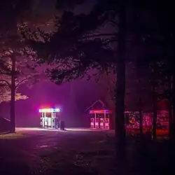 A night shot of a glowing gas pump in between trees