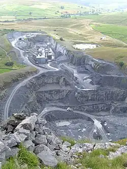 A deep quarry sunk below the surrounding ground, with upland marshes and fields beyond