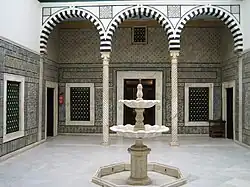 Patio du Petit Palais avec une fontaine de marbre au milieu de la cour et une colonnade.
