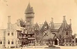 Sepia postcard photograph of ivy-clad sandstone mansion