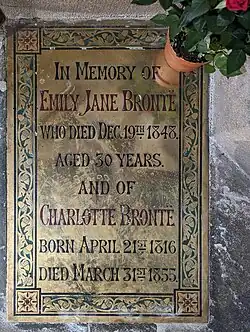 A brass plaque, bearing the names of Emily and Charlotte Bronte.