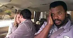 A white man and woman in business attire touch their foreheads smiling. A black man in a blue dress shirt holds his right hand against his forehead.