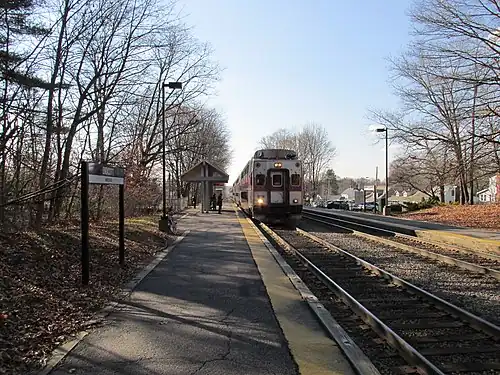 A passenger train at a suburban railway station with low platforms