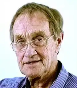 Colour Press photo of a clean-shaven, very elderly, bespectacled man, with sandy-coloured hair.