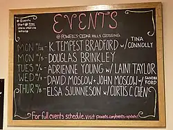 A chalkboard at Powell's Books listing upcoming author appearances, including Sjunneson