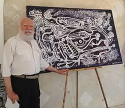 Frankétienne poses in front of his acrylic on canvas.