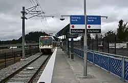 The platform of Gateway North station showing the station's shelter and a MAX train pulling in, facing north